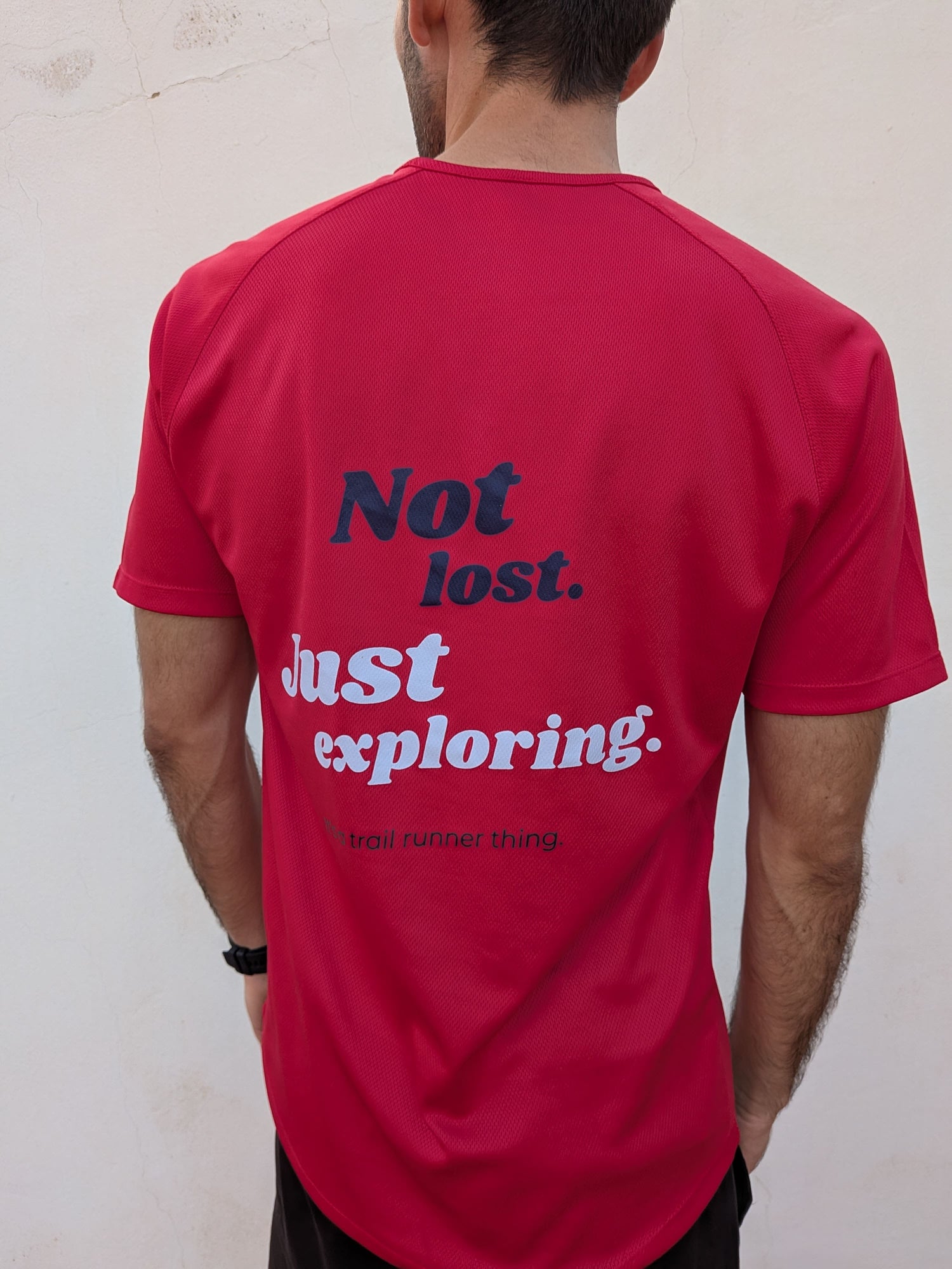 Camiseta trail running de color rojo con la inscripción "Not lost, just exploring". Camiseta deportiva para runner.